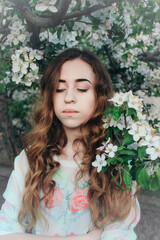 A girl with her eyes closed. Close-up portrait of a girl with long hair among the branches of a blossoming apple tree