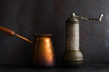 Traditional Turkish coffee and concept. Copper coffee pot. Cezve, vintage coffee grinder on a dark background.