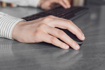 Business woman clicking mouse and typing on keyboard at work