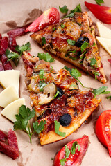 Two slice of pizza with olives, eggplant, salami and tomatoes