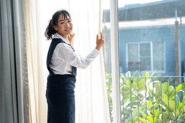Maid are adjusting curtains after cleaning hotel room.