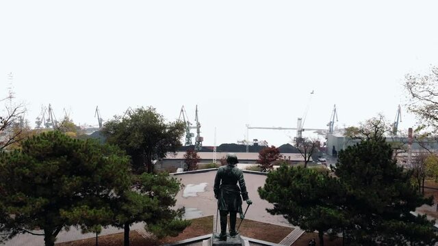 Aerial view of the square with a statue on a pedestal on the city embankment and the cargo seaport with. statue of Peter the great in Taganrog