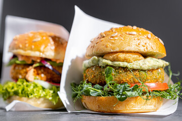 vegetarian, vegan burger with whole wheat buns, tomatoes, onions, vegan mayonnaise and spinach on a fresh bun with flaxseed and sesame seeds, surrounded by spinach leaves.