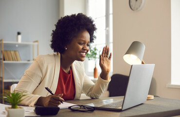 Friendly african american businesswoman holds an online meeting while sitting in the office. Woman...