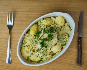 Delicious Hake on a green sauce with parsley leaves in a ceramic platter with wooden cutlery. Top View