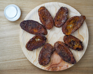 Traditional homemade and Delicious Spanish Torrijas making a circle on a round wooden plate and a glass of sugar. Top view