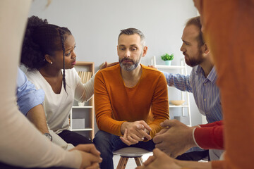 Multiracial people communicate and support each other in group therapy session. Patients comforting and reassuring upset unhappy mature man. We're here for you with honesty, compassion and empathy - obrazy, fototapety, plakaty