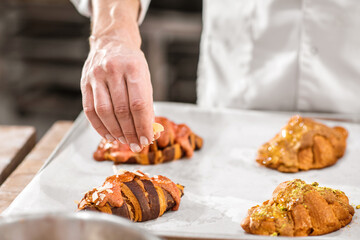 Hand sprinkling the croissants with nut chips