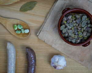 Habas a la Catalana, Tasty stew of beans in a clay bowl decorated with its ingredients. Top view