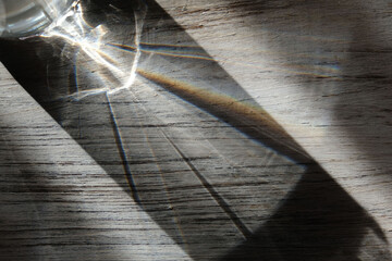 Obraz premium Wooden grey abstract background with light and shadows caustic effect. Light passes through a glass. Blurred light refraction texture overlay. effect like a space theme