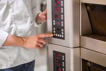 Finger of mans hand touching control button of oven