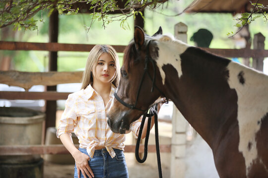 A woman in a cowgirl style sits in a horse ranch with a western farm environment.
