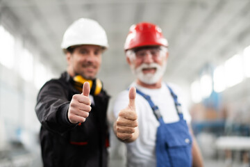 Portrait of workers in factory. Colleagues showing thumbs up.