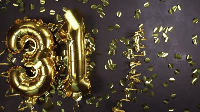 golden foil balloon number thirty-one. Birthday or anniversary card with the inscription 31 Black concrete background. Anniversary celebration. copy space