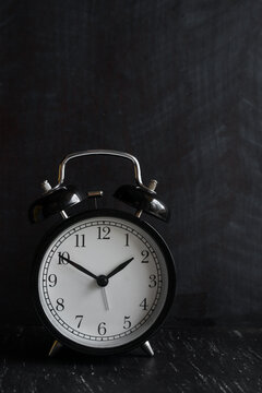 Retro alarm clock on wooden table Against Black Background