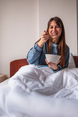 Fototapeta na wymiar Woman eating cereal for breakfast in bed