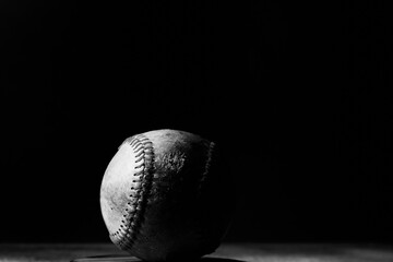 Dark baseball ball close up with black background.