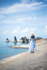 Woman traveler wearing blue dress and straw hat enjoying at Hin Ta and Hin Yai Rocks during summer at Koh Samui Island, Surat Thani Province, Thailand.