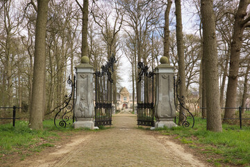 Horizontal landscape of a country road with a castle gate and old trees leading to kasteel Heeswijk...