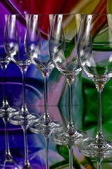 Diagonal of five empty wine glasses on a colored abstract background and reflective surface