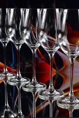 Diagonal of five empty wine glasses on a colored abstract background and reflective surface