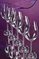 Diagonal of five empty wine glasses on a colored abstract background and reflective surface