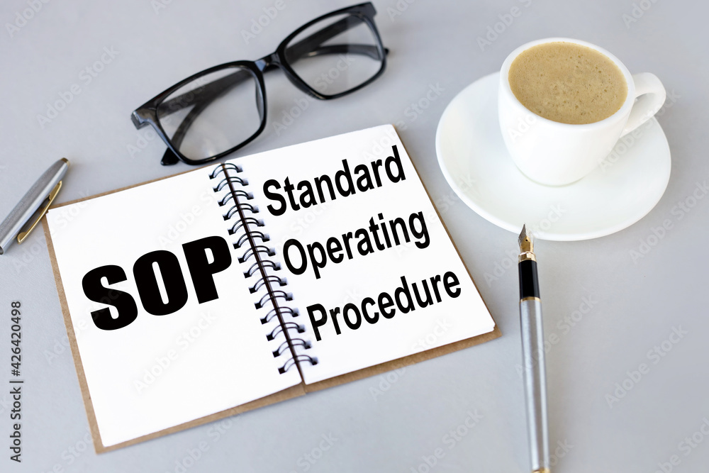 Aufkleber standard operating procedure. sop. text on white notepad paper. near cups with coffee and plants on 