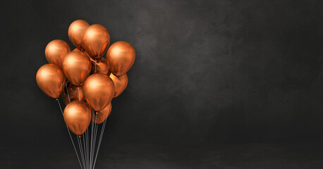 Copper balloons bunch on a black wall background. Horizontal banner.