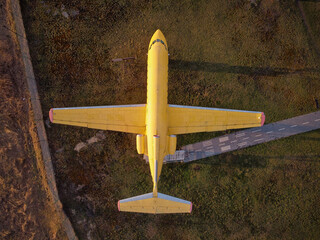 aerial view from drone of a small old jet yellow passenger plane standing in a field