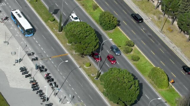 aerial view flowing traffic on a main street in Madrid. there are trees between the lanes.Paseo de la Castellana