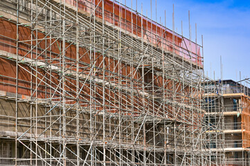 Scaffolding around the outside of a new block of flats under construction. No people.