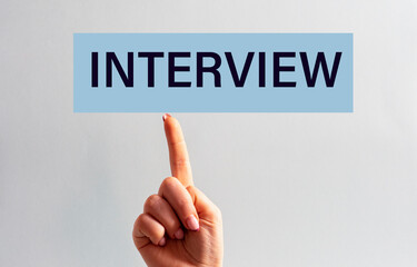 The woman's index finger of the hand is directed to the sign with the inscription - INTERVIEW
