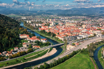 Fototapeta na wymiar Scenic aerial view of the Celje city in Slovenia, Styria from old castle ancient walls. Amazing landscape with town in Lasko valley, river Savinja and blue sky with clouds, outdoor travel background