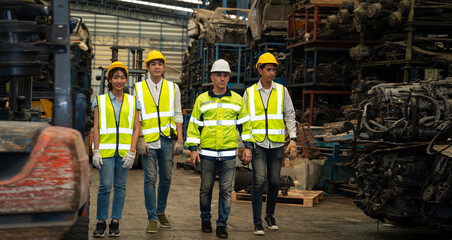 A group of engineers are walking in an auto parts factory. The chief engineer walks ahead of the other engineers. He's the leader of a successful team in teamwork and diversity worker concept.