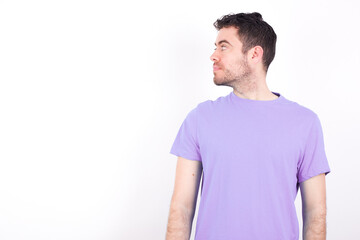 Obraz premium Side view of young happy smiling young handsome caucasian man wearing purple t-shirt against white background 