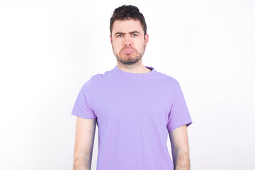 Obraz premium young handsome caucasian man wearing purple t-shirt against white wall crying desperate and depressed with tears on his eyes suffering pain and depression. Sad facial expression and emotion concept.