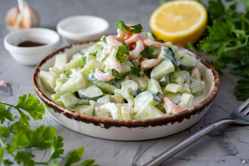Diet breakfast: a salad of shrimp and fresh vegetables on a beautiful white plate on a gray background. Close-up