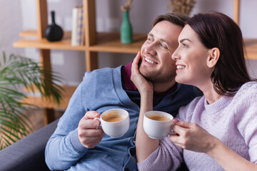 Smiling woman with cup of coffee touching husband