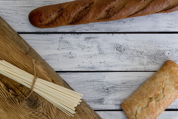Bread, bun, focaccia, ciabatta, udon, pasta, flour products on a wooden background. Mediterranean...