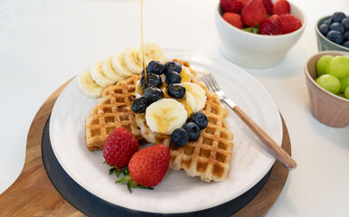 Delicious croffle dessert with fruits and maple syrup.