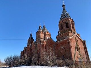 Old brick abandoned orthodox Church of the Trinity. Spring view with meadow

