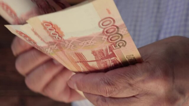 Close Up Of Male Hands Counting Russian Rubles On Wooden Background. Bills Of Five Thousand Rubles In Hand.