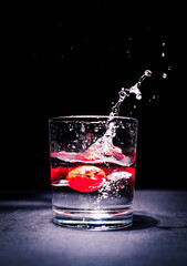 Tomate fällt in Wasserglas