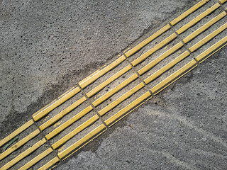 Abandoned dirty yellow tactile tiles is laid on the asphalt, top view.