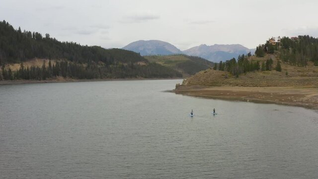 drone shot of people paddle boarding on large lake reservoir