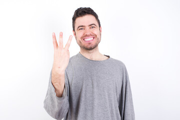 Fototapeta premium young handsome caucasian bearded man wearing pyjama over white wall smiling and looking friendly, showing number three or third with hand forward, counting down