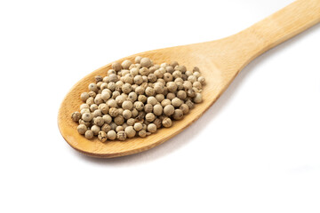 Closeup of white pepper grains on a wooden spoon isolated over white background