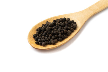 Closeup of black pepper grains on a wooden spoon isolated over white background