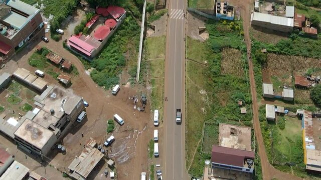 Aerial view following a truck driving through a small town, in rural Africa - top down, drone shot