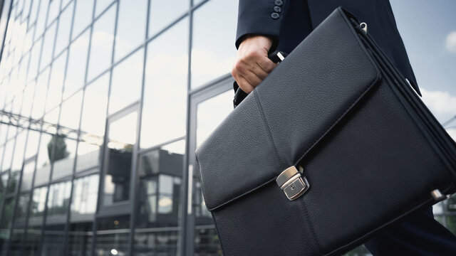 cropped view of businessman holding leather briefcase.